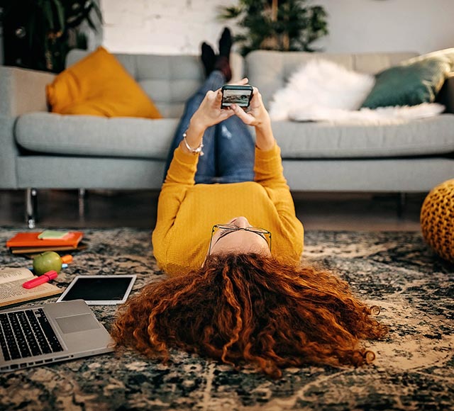 Woman laying on the floor using her phone